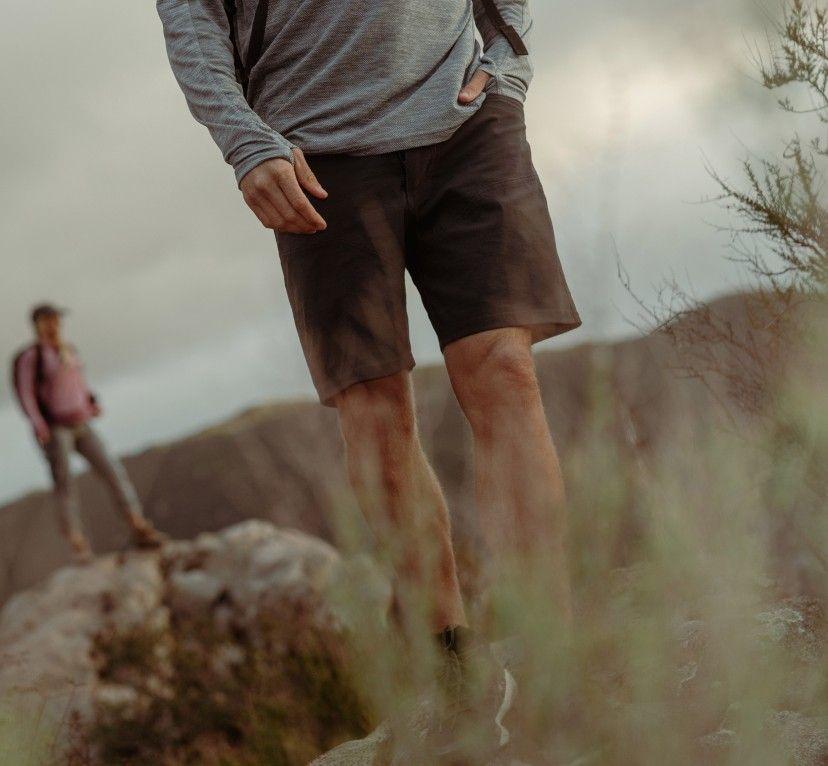 A man on a hike in KUHL shorts with a woman in the background