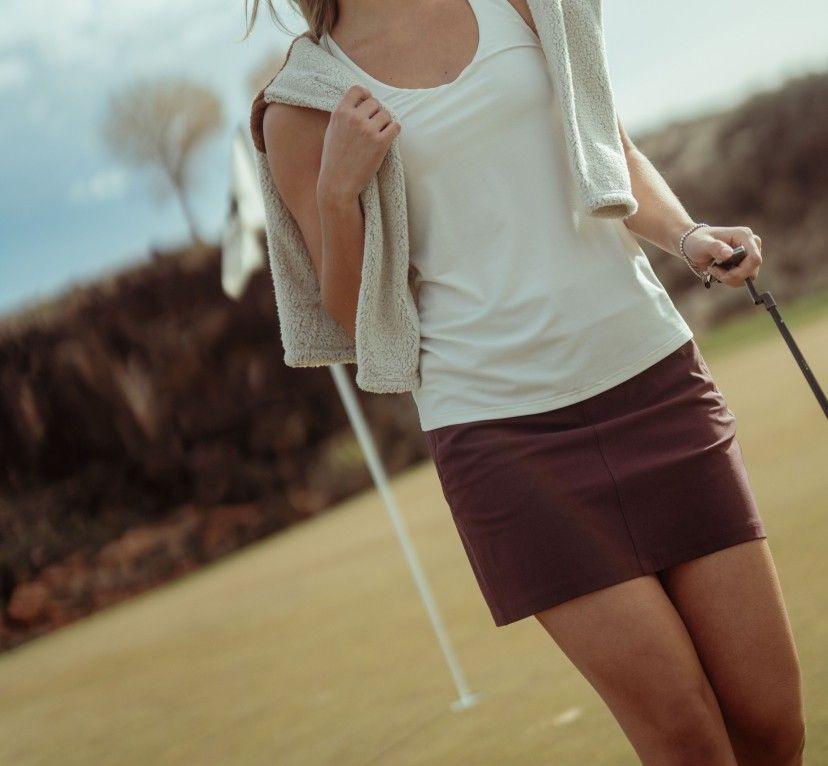 A woman playing golf wearing a KUHL skort