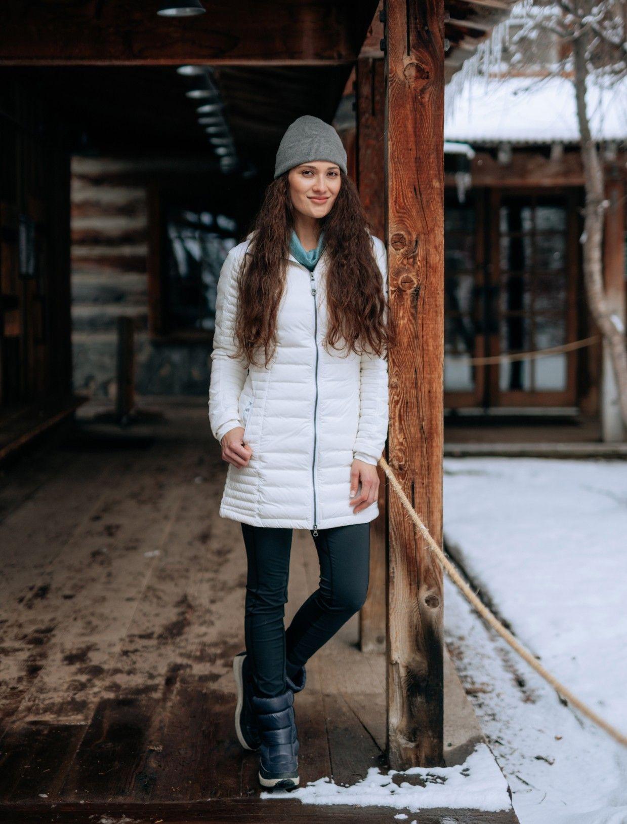 Woman wearing a KUHL parka on a snowy deck