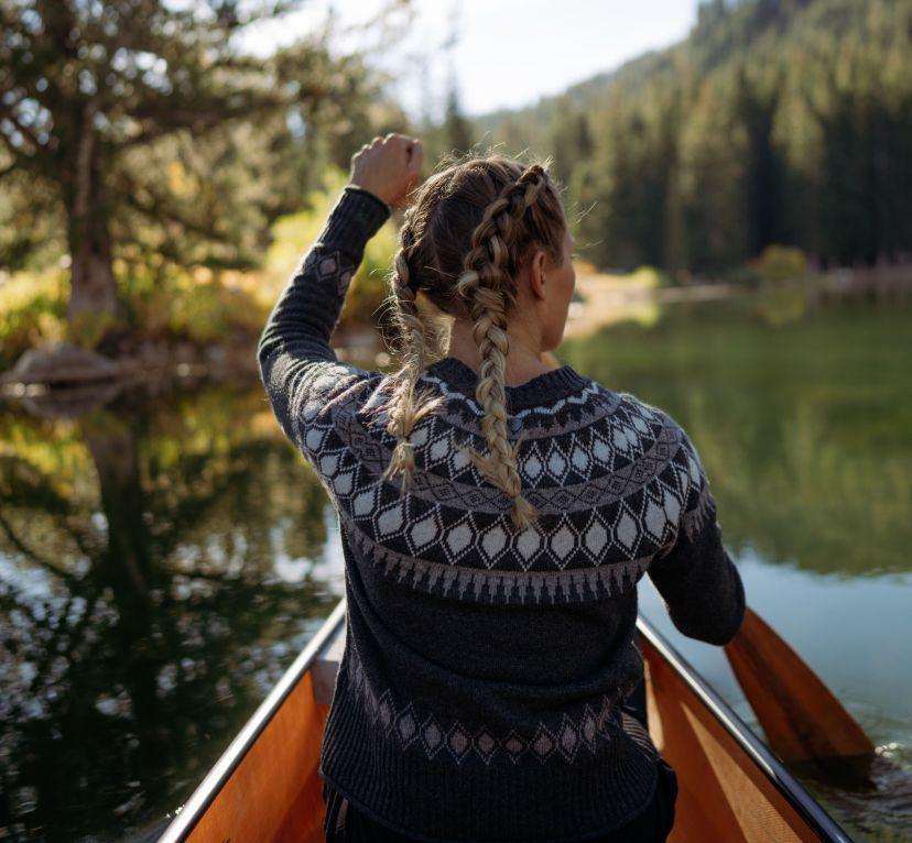 A woman at a lake wearing her Kühl Wunderland™ Sweater.