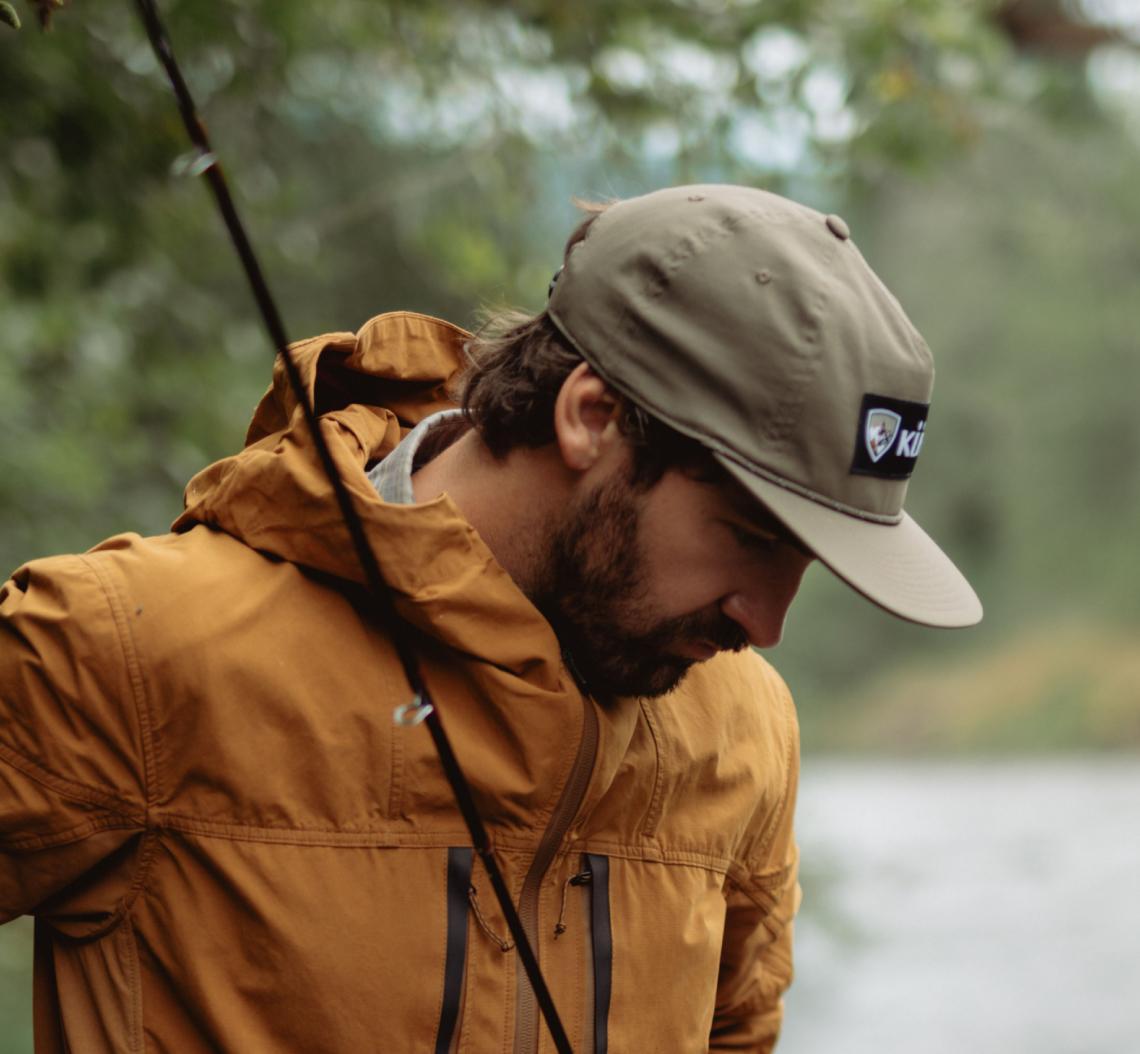 A man fishing and wearing his The Outsider® jacket and his Renegade™ Camp Hat.