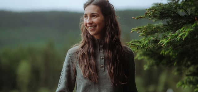 A woman outside on her truck wearing a Kühl Sofie™ Sweater.